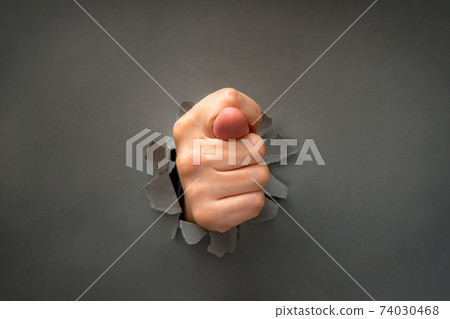 Fig gesture through the hole in a grey paper 74030468