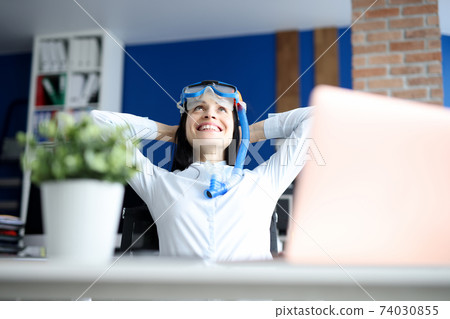 Woman in diving mask dreaming of sea at workplace 74030855