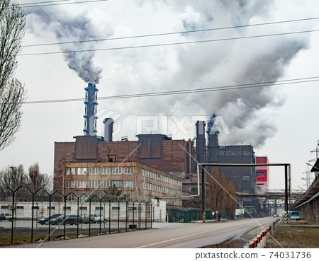 Dense thick smoke comes from industrial chimney pipes. Pipes with smoke, industrial production Dense thick smoke comes from industrial chimney pipes. Pipes with smoke, industrial production 74031736