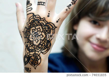 Teen girl shows patterns by henna drawn on her hand Teen girl shows patterns by henna drawn on her hand 74031835