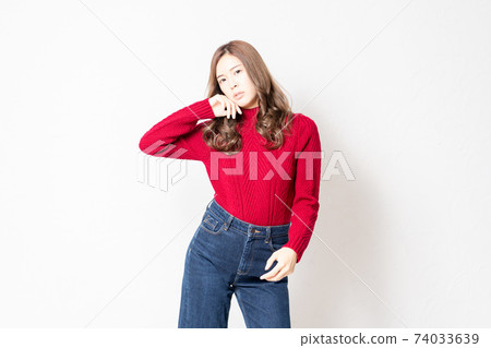 一件紅色的毛衣,站在白牆前和構成一個年輕女子 一件紅色的毛衣,站在白牆前和構成一個年輕女子 74033639