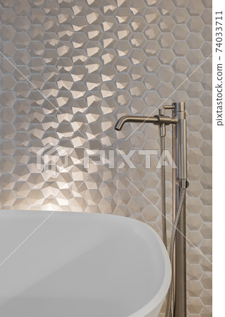 Metal faucet and shower in bathroom with hexagon tiles and white bath tub Metal faucet and shower in bathroom with hexagon tiles and white bath tub 74033711