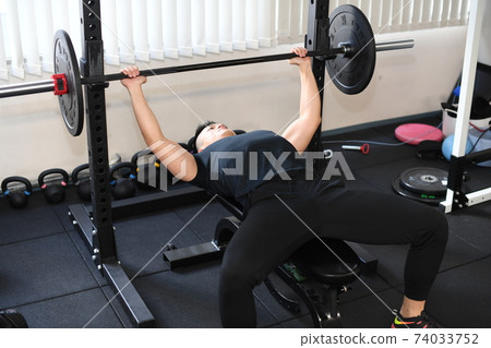 Macho man giving a bench press at the gym Macho man giving a bench press at the gym 74033752
