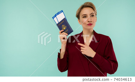 A modern trendy smiling woman in red suit with air tickets and a passport in her hand. A modern trendy smiling woman in red suit with air tickets and a passport in her hand. 74034613