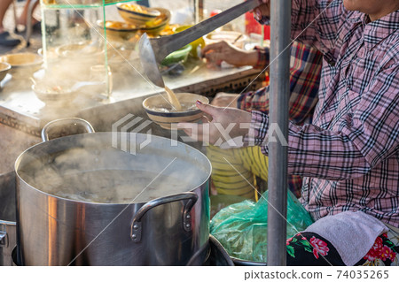 Vietnamese woman selling pig organs porridge at street food vendor Vietnamese woman selling pig organs porridge at street food vendor 74035265