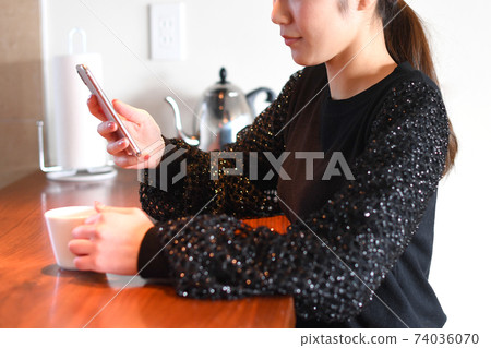 在操作智能手機的下午茶時間的年輕女子 在操作智能手機的下午茶時間的年輕女子 74036070