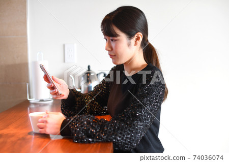 在操作智能手機的下午茶時間的年輕女子 在操作智能手機的下午茶時間的年輕女子 74036074