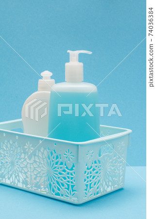 Bottles of dishwashing liquid in basket on blue background. 74036384