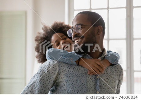 Close up happy African American father piggy backing little daughter 74036814