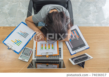 Aerial view of woman falling asleep on desk at office Aerial view of woman falling asleep on desk at office 74036917