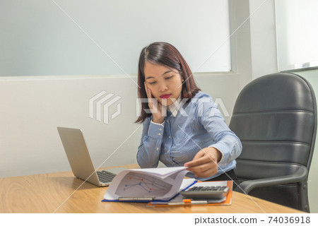 Female manager reading financial reports and working on laptop Female manager reading financial reports and working on laptop 74036918