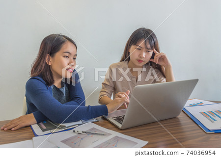 Two young ladies working on laptop and financial paperworks 74036954