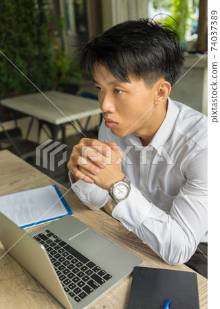 Vertical photo of young Asian businessman thinking 74037389