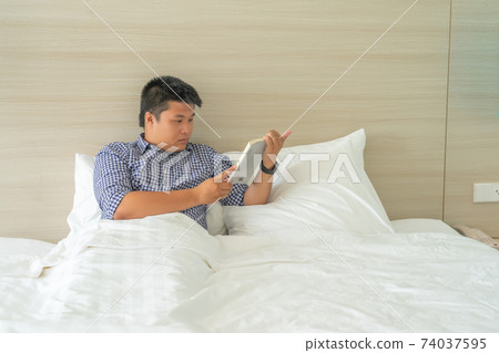 Businessman reading book on the bed in free time Businessman reading book on the bed in free time 74037595