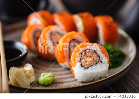 Sushi maki rolls with spicy crab, salmon, cucumber on a plate with chopsticks, soy sauce, wasabi and ginger. Japanese traditional seafood served for lunch in modern gourmet restaurant 74038316