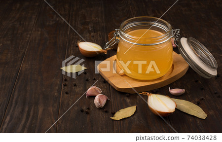 Traditional homemade beef bone broth with vegetable in glass jar on dark rustic wooden background. Traditional homemade beef bone broth with vegetable in glass jar on dark rustic wooden background. 74038428