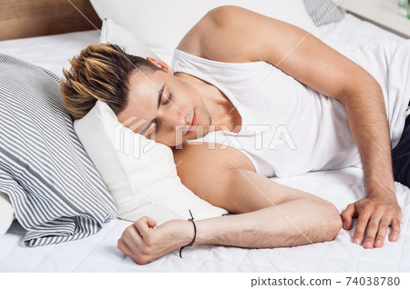 Man sleeping on a white pillow and a mattress on a wooden bed. Concept of comfortable sleep. orthopedic mattress and pillow Man sleeping on a white pillow and a mattress on a wooden bed. Concept of comfortable sleep. orthopedic mattress and pillow 74038780