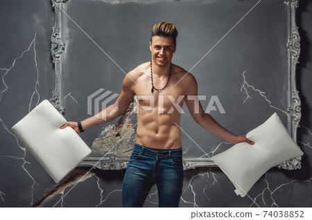 Man with two white pillows in hands on a gray background. Concept of comfortable sleep. orthopedic mattress and pillow 74038852
