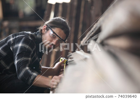 Carpenter, joiner is working in the workshop. Man at work on wood.Image of mature carpenter in the workshop,furniture making concept. 74039640