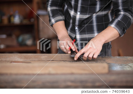 Carpenter, joiner is working in the workshop. Man at work on wood.Image of mature carpenter in the workshop,furniture making concept. 74039643