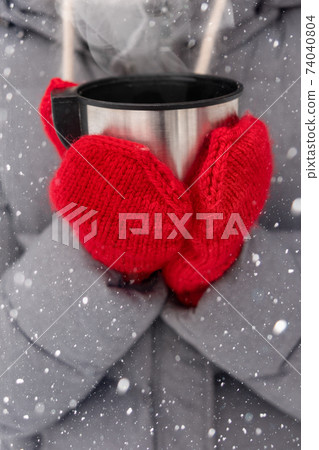 hands in red mittens holding a cup of tea 74040804