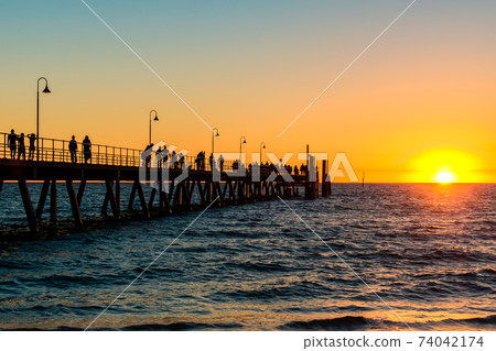 Glenelg Beach jetty with people at sunset Glenelg Beach jetty with people at sunset 74042174
