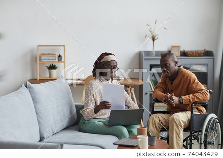 Businesswoman Consulting Wheelchair User at Home Businesswoman Consulting Wheelchair User at Home 74043429