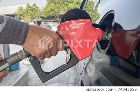 Close up employees pressed their hands with the petrol dispenser to refuel in the car's tank at the petrol station, Refuel Service balsin or diesel to the petrol pump concept. Close up employees pressed their hands with the petrol dispenser to refuel in the car's tank at the petrol station, Refuel Service balsin or diesel to the petrol pump concept. 74043659