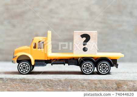 Toy truck hold alphabet letter block question mark on wood background 74044620
