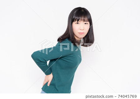 A woman standing in front of a white background with her hands on her hips A woman standing in front of a white background with her hands on her hips 74045769