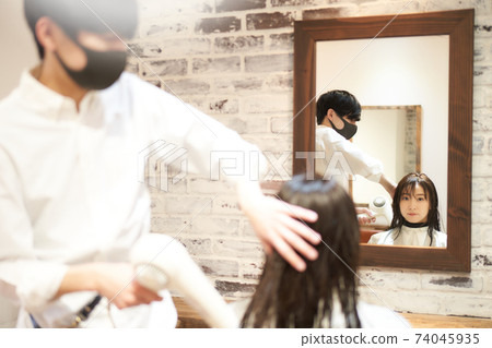 戴著面具和年輕的女性顧客的美容師的形象 74045935