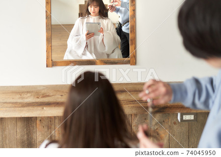Female customer having a haircut while looking at a tablet 74045950
