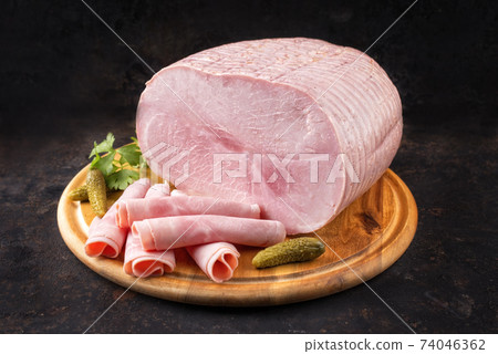 German boiled ham as piece and sliced decorated with gherkin  74046362