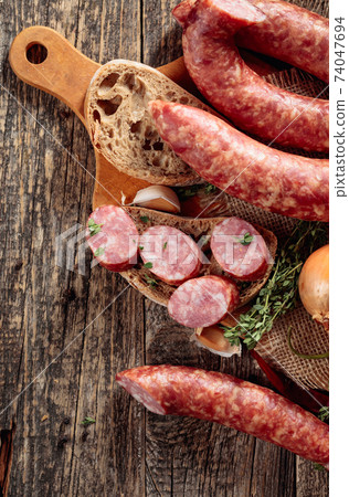 Sausage with bread and spices on a old wooden table. Sausage with bread and spices on a old wooden table. 74047694