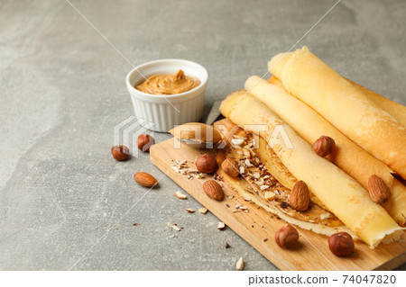 Concept of delicious breakfast with crepes with peanut butter and nuts on gray table 74047820