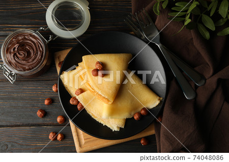 Concept of breakfast with crepes with chocolate paste and nuts on wooden table Concept of breakfast with crepes with chocolate paste and nuts on wooden table 74048086