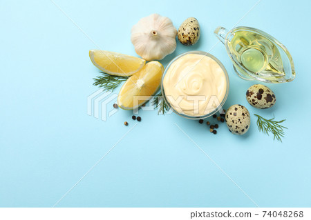 Bowl with mayonnaise and ingredients on blue background Bowl with mayonnaise and ingredients on blue background 74048268