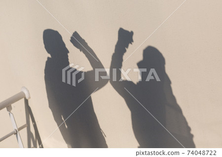 Elbow bumping safety greeting of two people shadow on wall of coronavirus COVID-19. New normal. 74048722