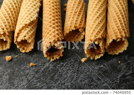 Wafer rolls with condensed milk on black smokey background 74048950