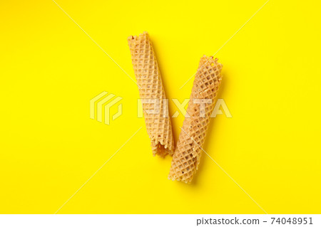 Tasty wafer rolls with condensed milk on yellow background Tasty wafer rolls with condensed milk on yellow background 74048951
