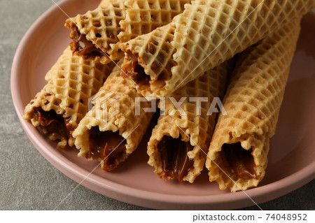 Plate with wafer rolls with condensed milk on gray background 74048952