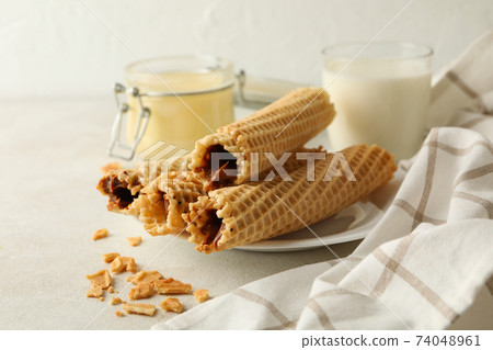 Concept of breakfast with wafer rolls with condensed milk on white textured background 74048961