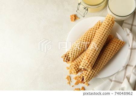 Concept of breakfast with wafer rolls with condensed milk on white textured background 74048962