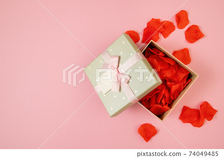Open box filled with rose leaves on pink background Open box filled with rose leaves on pink background 74049485