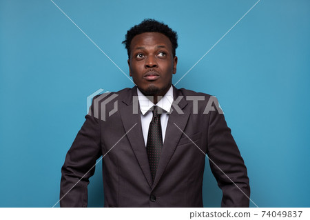 Smiling african American male in glasses and casual wear isolated on blue studio background look at blank copy space aside, happy black millennial man in eyewear consider good sale offer or deal Smiling african American male in glasses and casual wear isolated on blue studio background look at blank copy space aside, happy black millennial man in eyewear consider good sale offer or deal 74049837