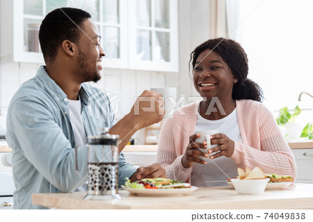 Morning Together. Romantic Black Couple Eating Breakfast And Drinking Coffee In Kitchen Morning Together. Romantic Black Couple Eating Breakfast And Drinking Coffee In Kitchen 74049838
