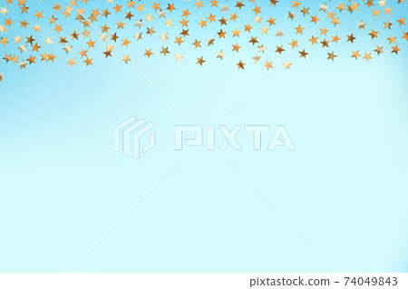 Stars golden glitter confetti isolated on blurred abstract blue background. Festive holiday background. Celebration concept. Falling magic gold particles. Invitation mock up. Top view, flat lay. 74049843