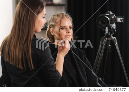 Beautiful woman beauty vlogger doing cosmetic makeup demonstration with her friend in studio Beautiful woman beauty vlogger doing cosmetic makeup demonstration with her friend in studio 74049877