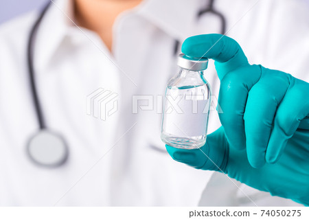Doctor with a stethoscope on shoulder holding syringe and COVID-19 vaccine. 74050275