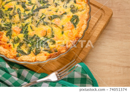 Salty pastries, salmon fish or seafood and spinach quiche pie - homemade recipe pie on wooden table background with copy space, selective focus. Top view Salty pastries, salmon fish or seafood and spinach quiche pie - homemade recipe pie on wooden table background with copy space, selective focus. Top view 74051374